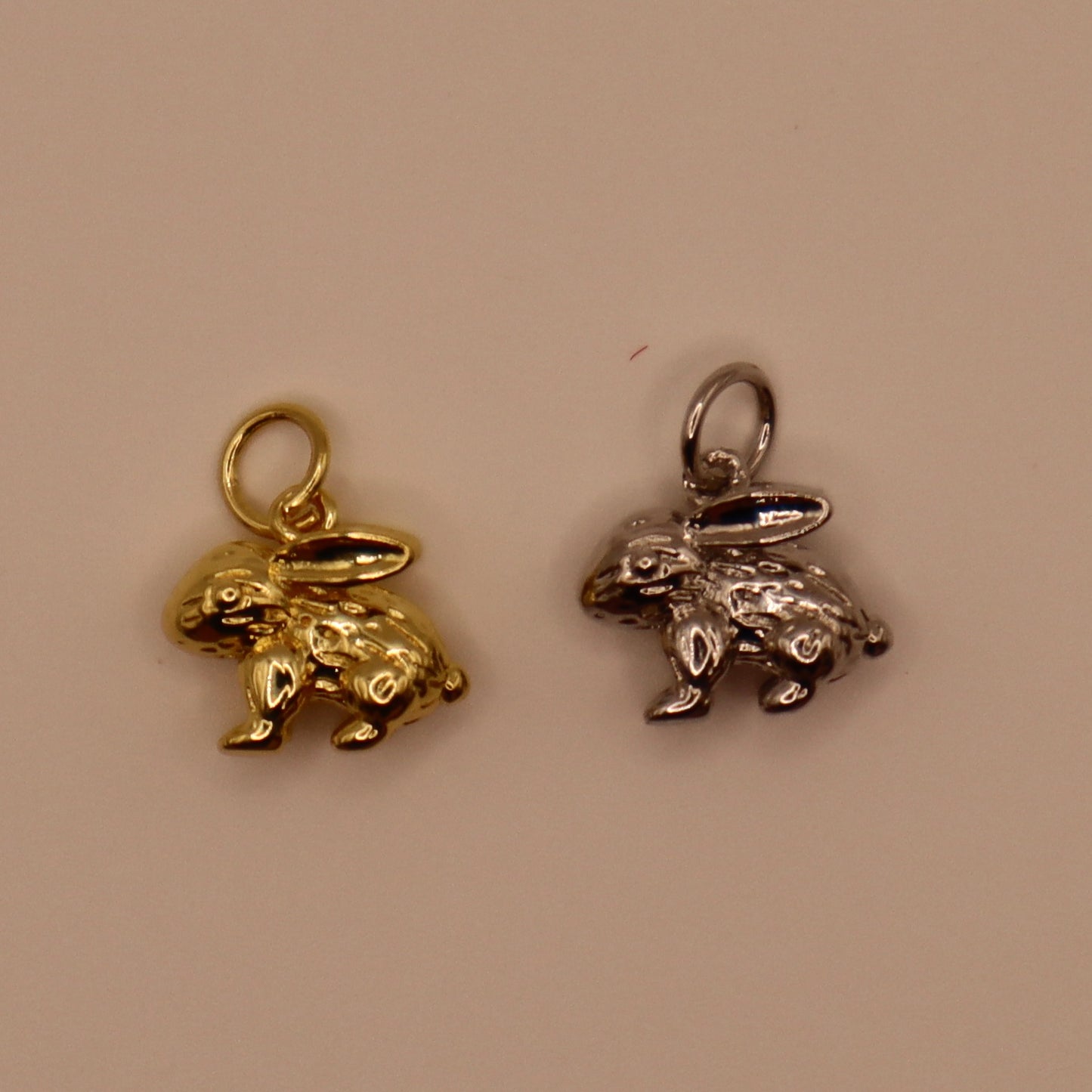 Gold and silver rabbit-shaped charms on a beige background