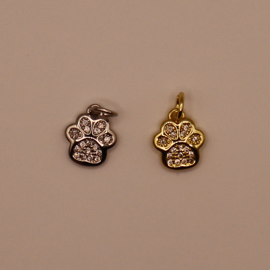 Two paw-shaped pendants, one silver and one gold, on a beige background.
