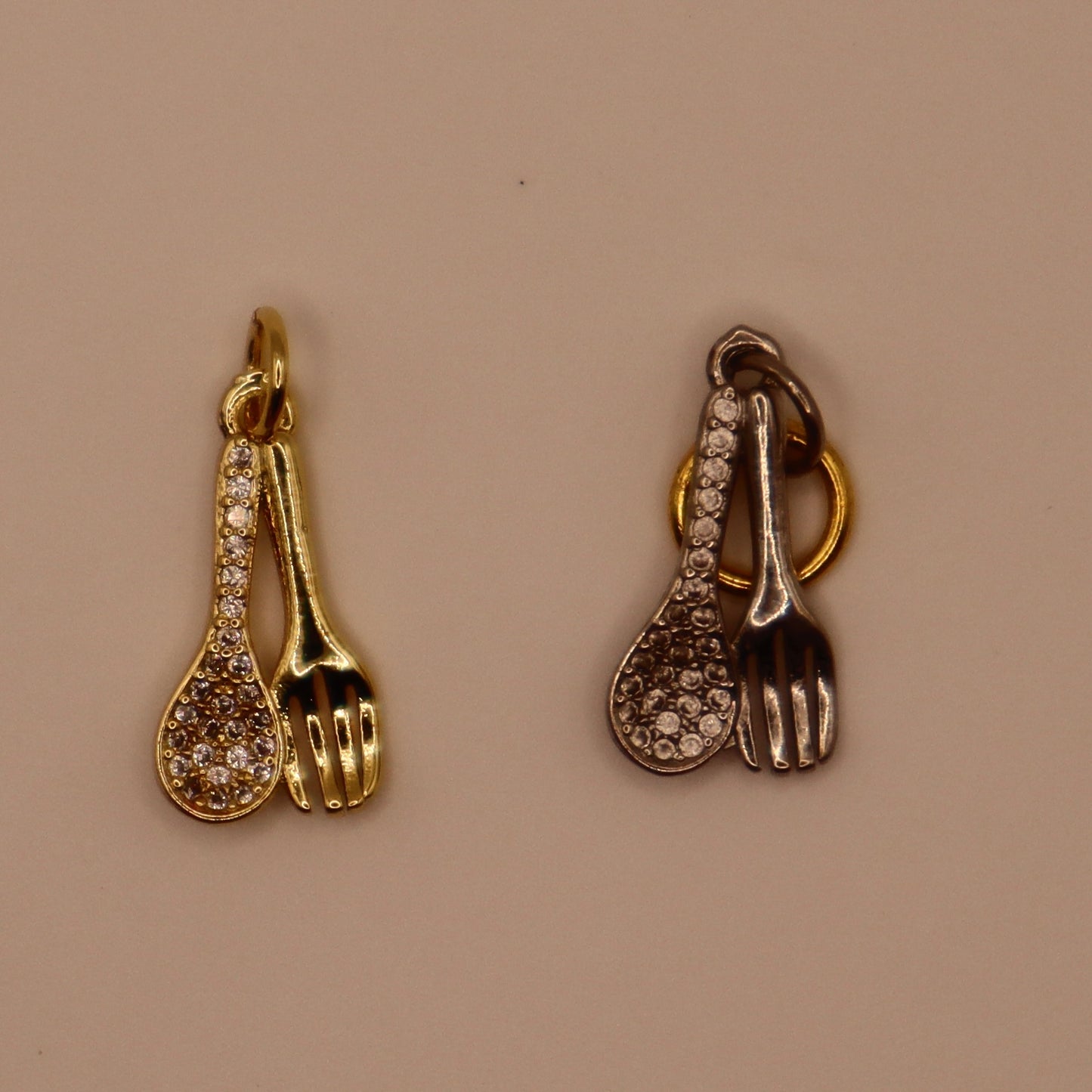 Gold and silver spoon and fork charms on a beige background