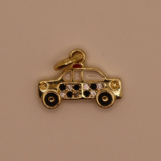 Gold taxi charm with embedded stones on a beige background