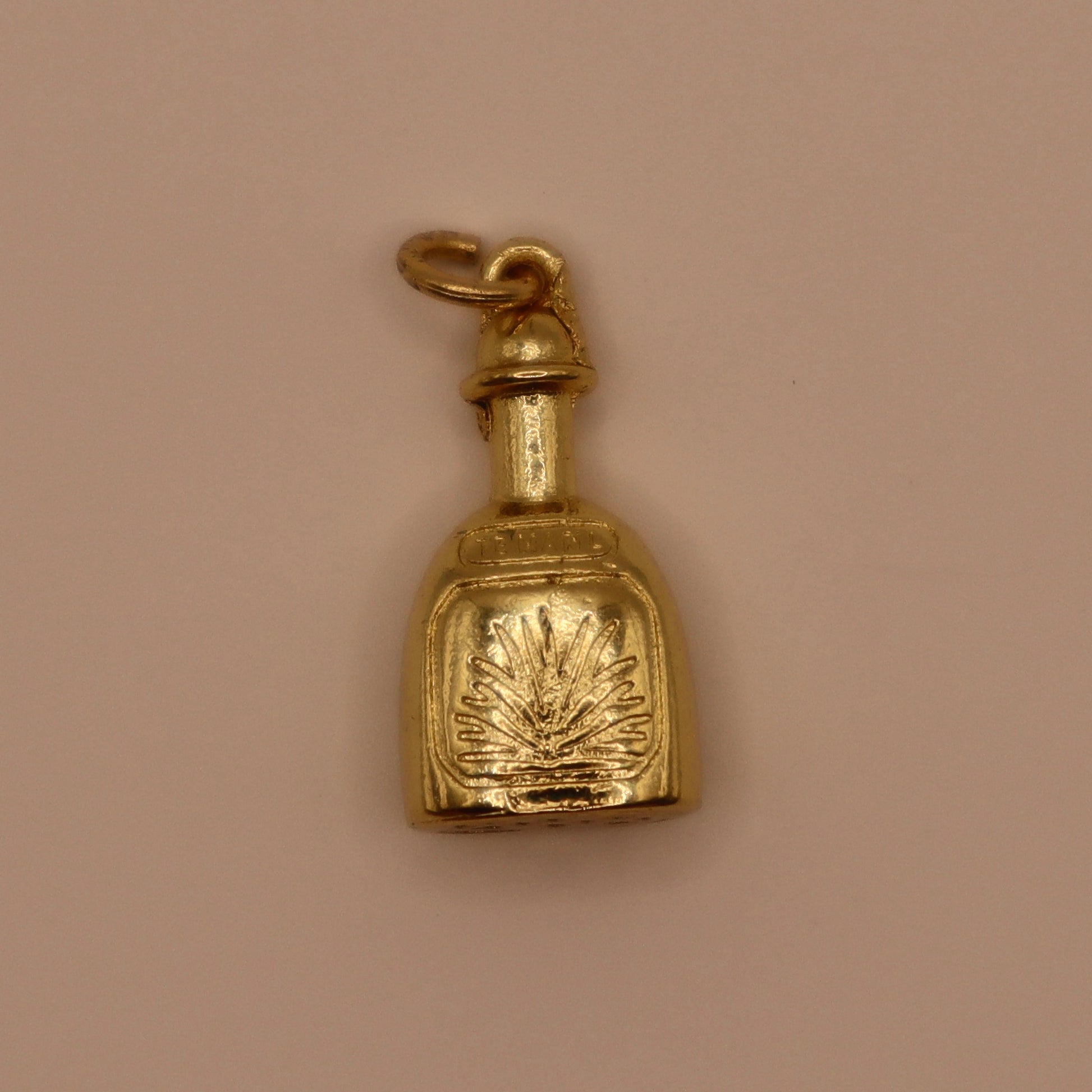 Gold tequila charm on a beige background