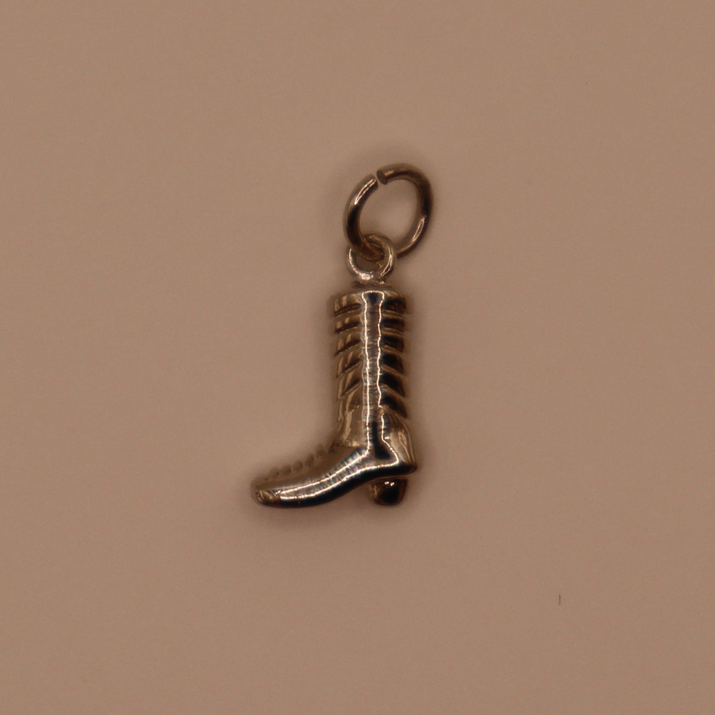 Silver boot charm on a beige background