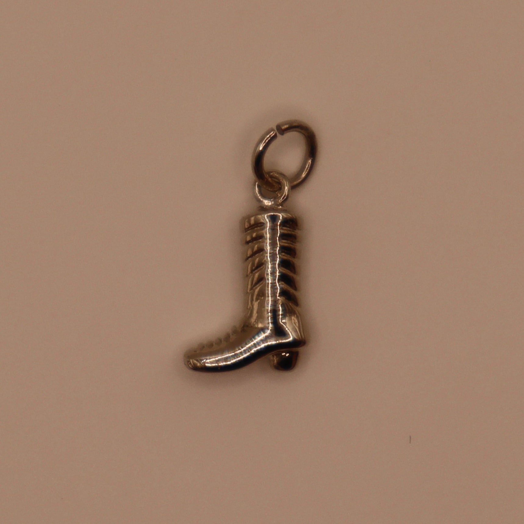 Silver boot charm on a beige background