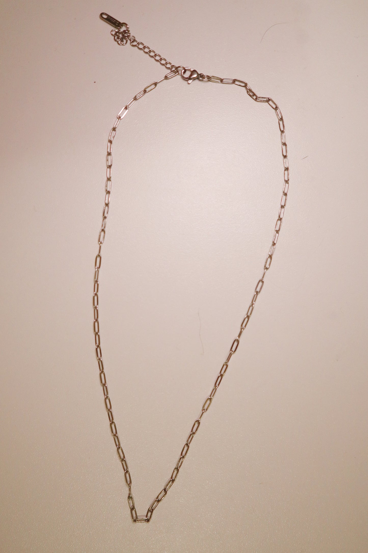 silver dainty chain necklace on a beige background