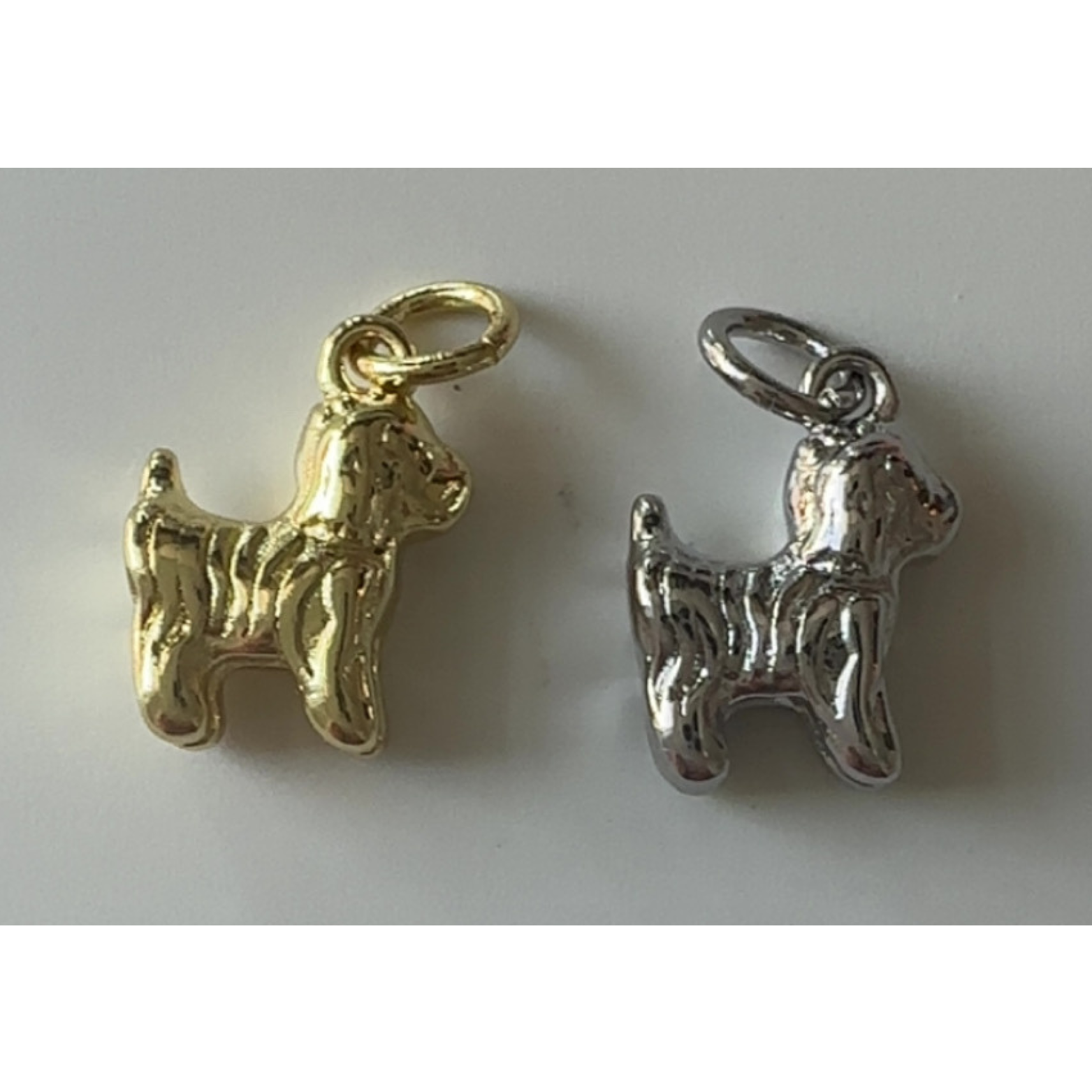 Gold and silver dog-shaped charms on a white background