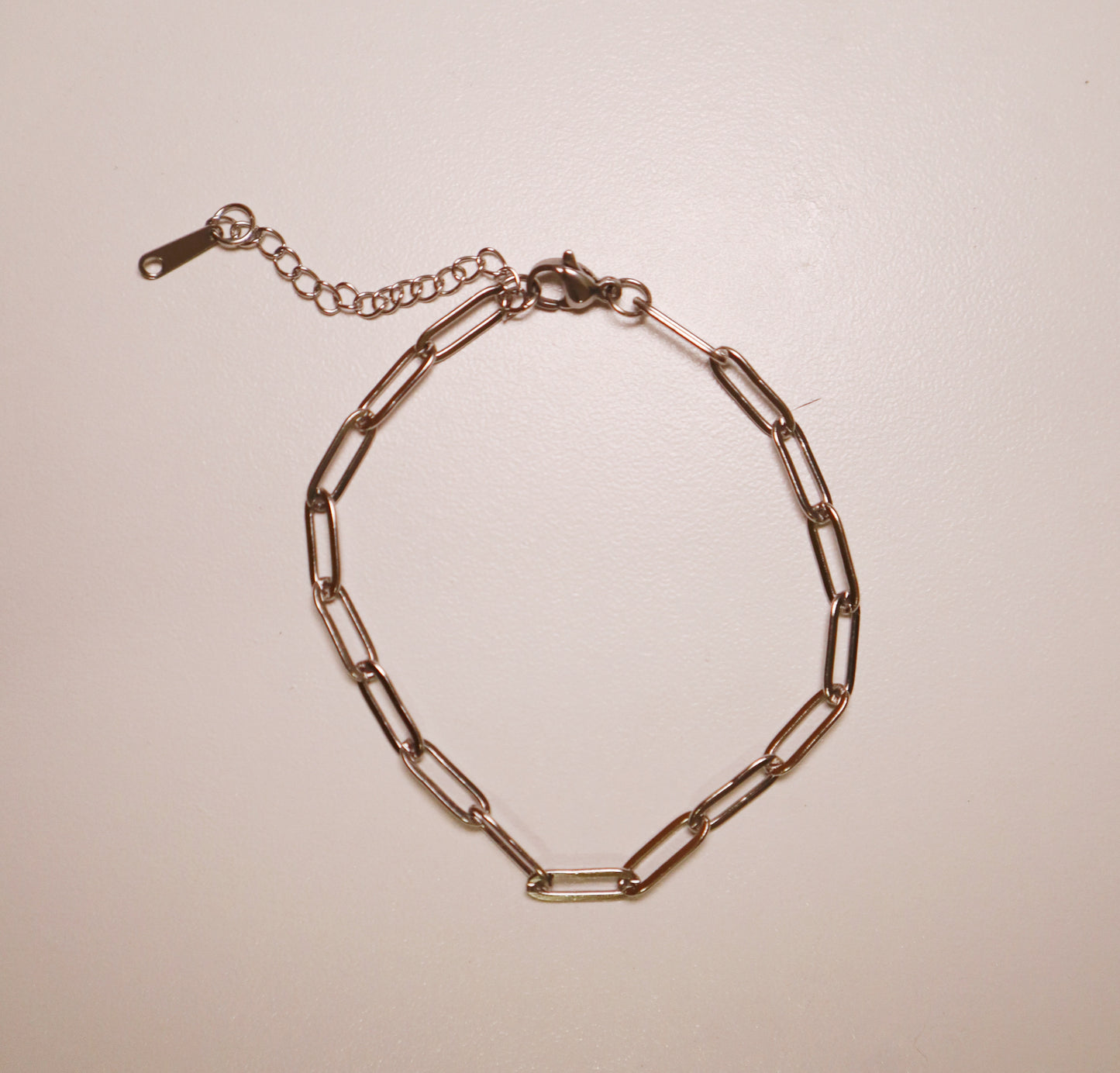 silver paperclip bracelet chain bracelet on a beige background