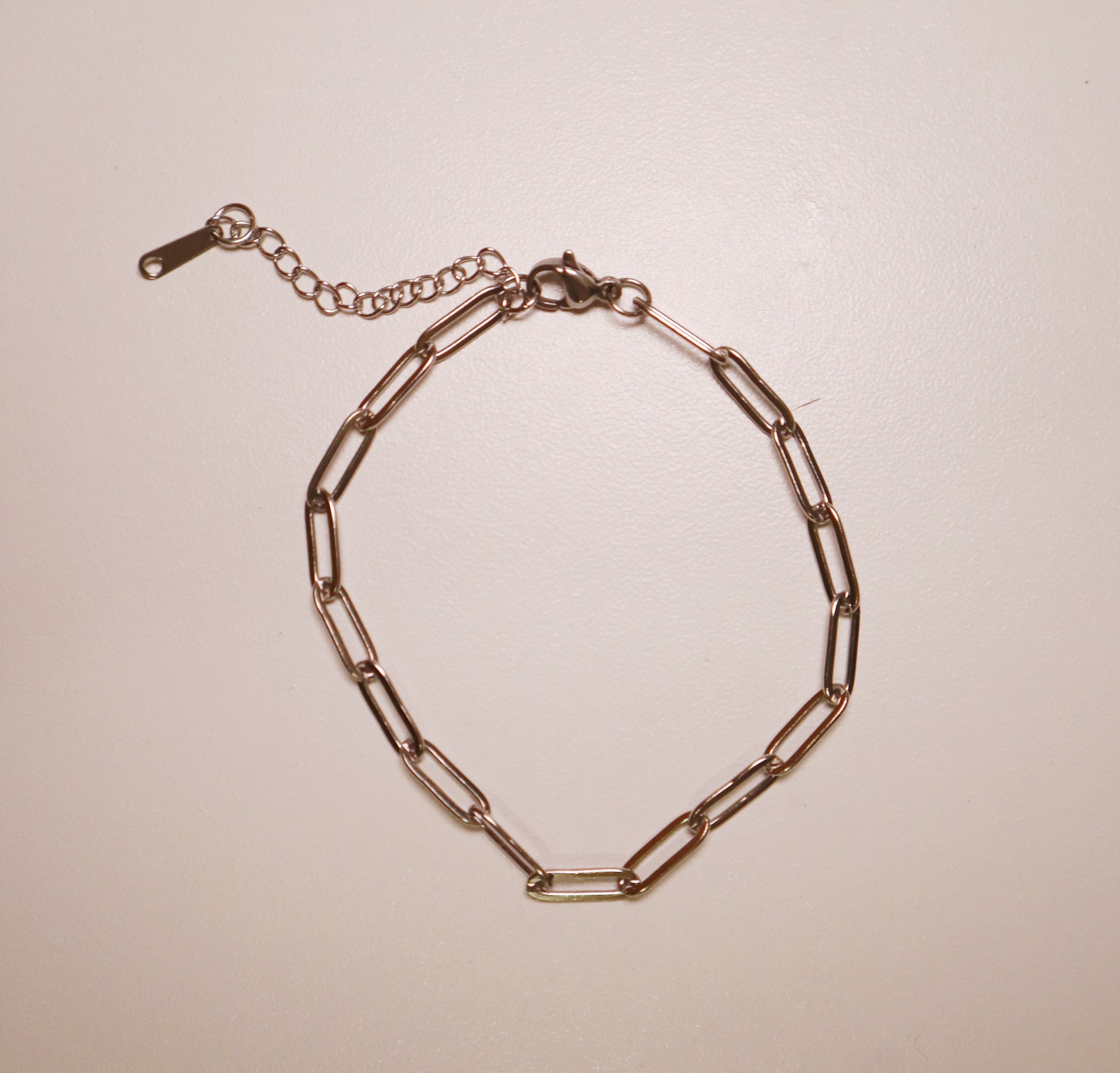 silver paperclip bracelet chain bracelet on a beige background