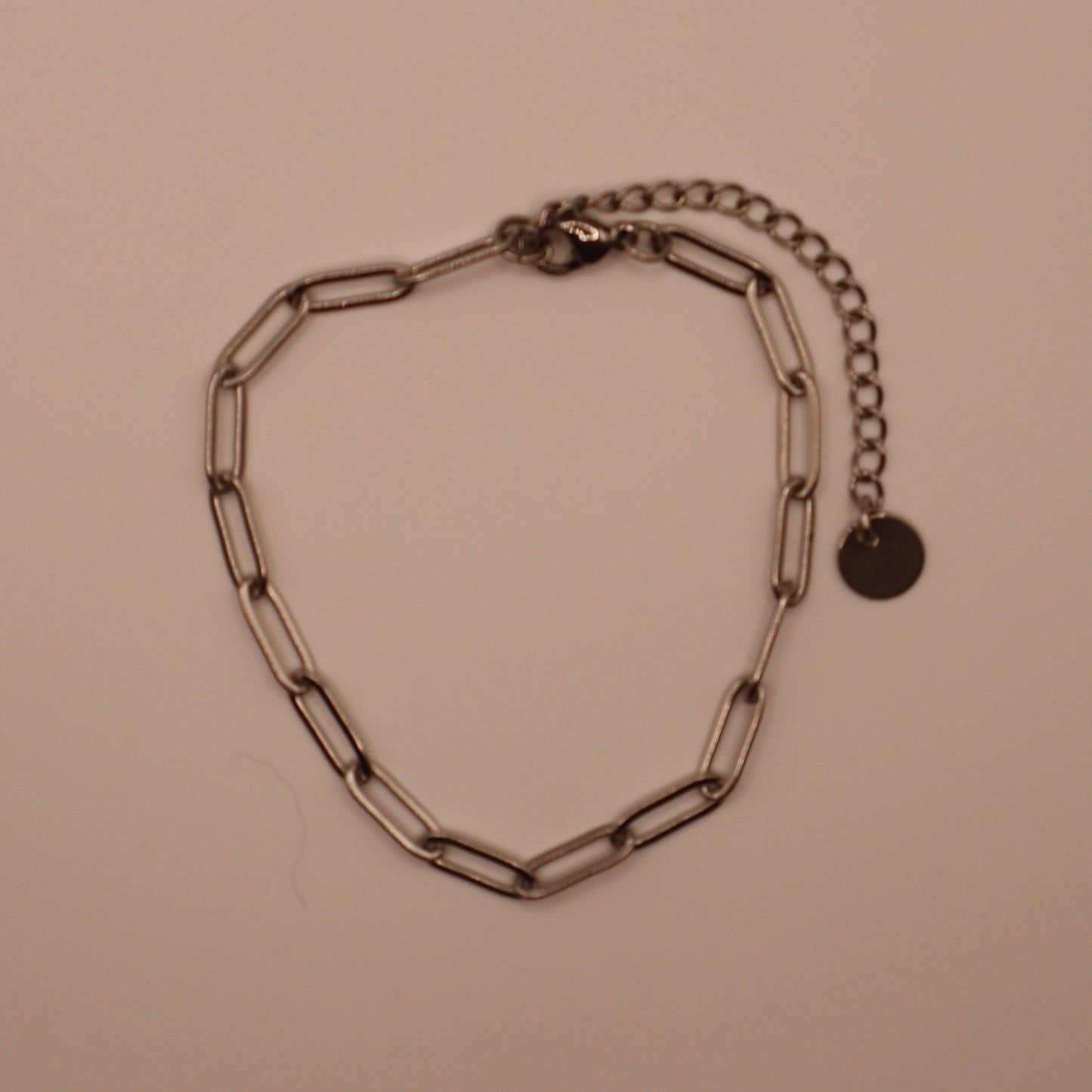 Silver chain paperclip bracelet on a beige background