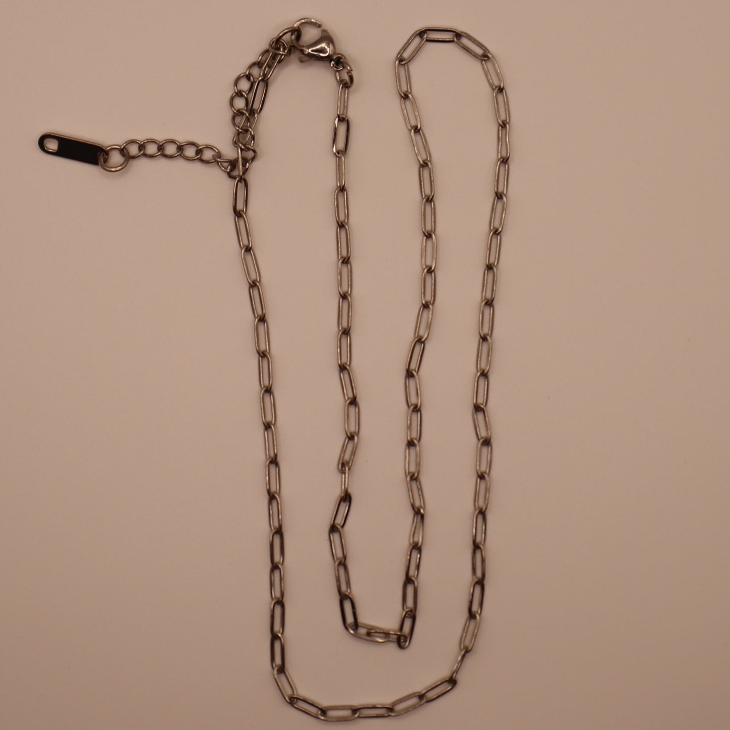 Silver paperclip necklace on a beige background