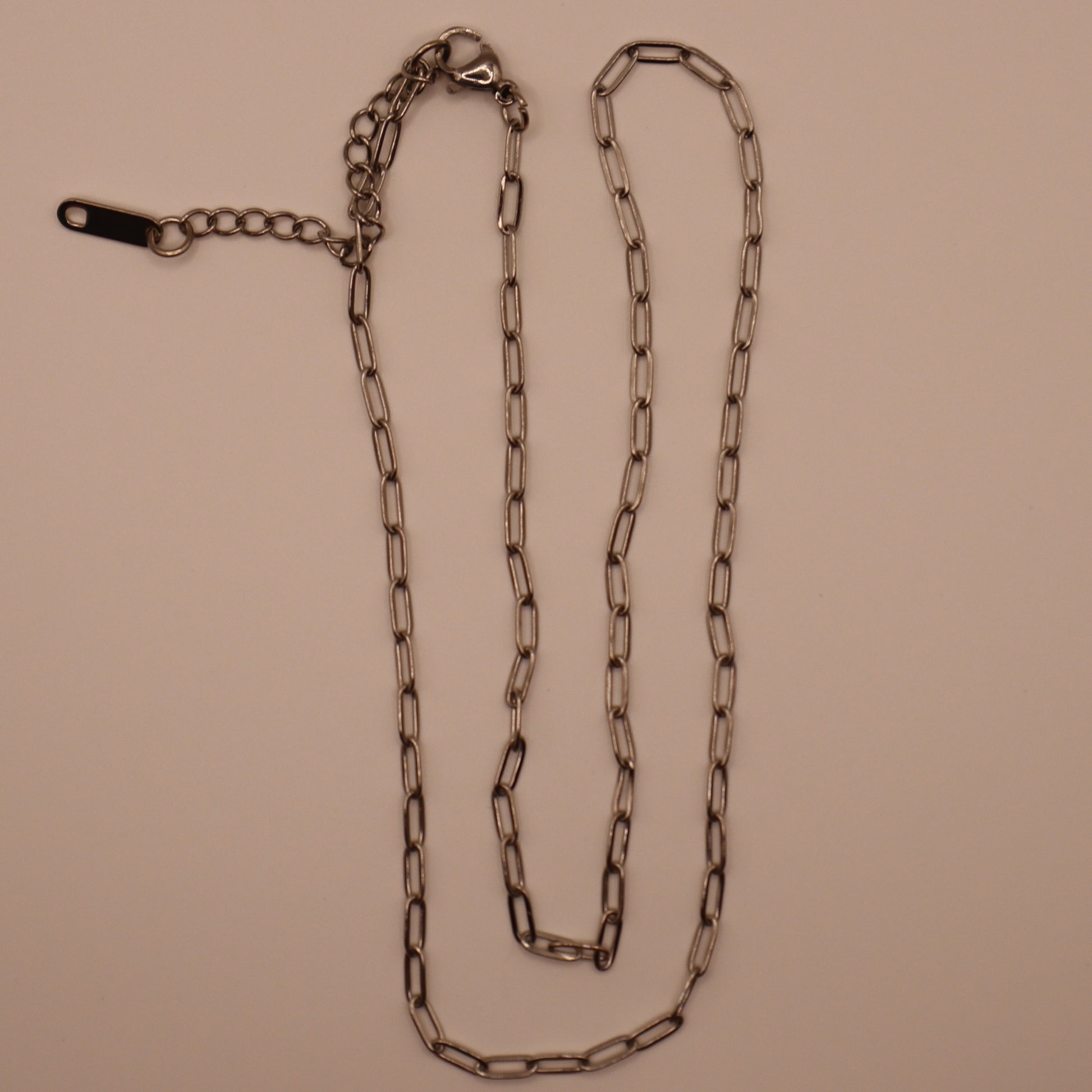 Silver paperclip necklace on a beige background