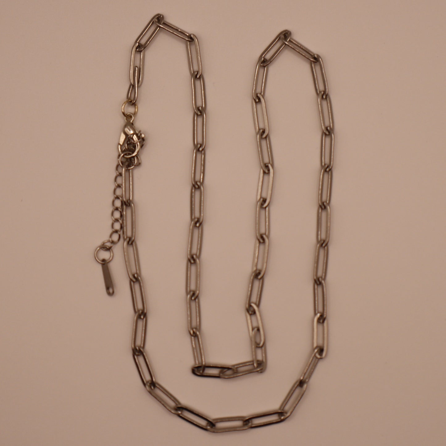 Silver paperclip necklace on a beige background