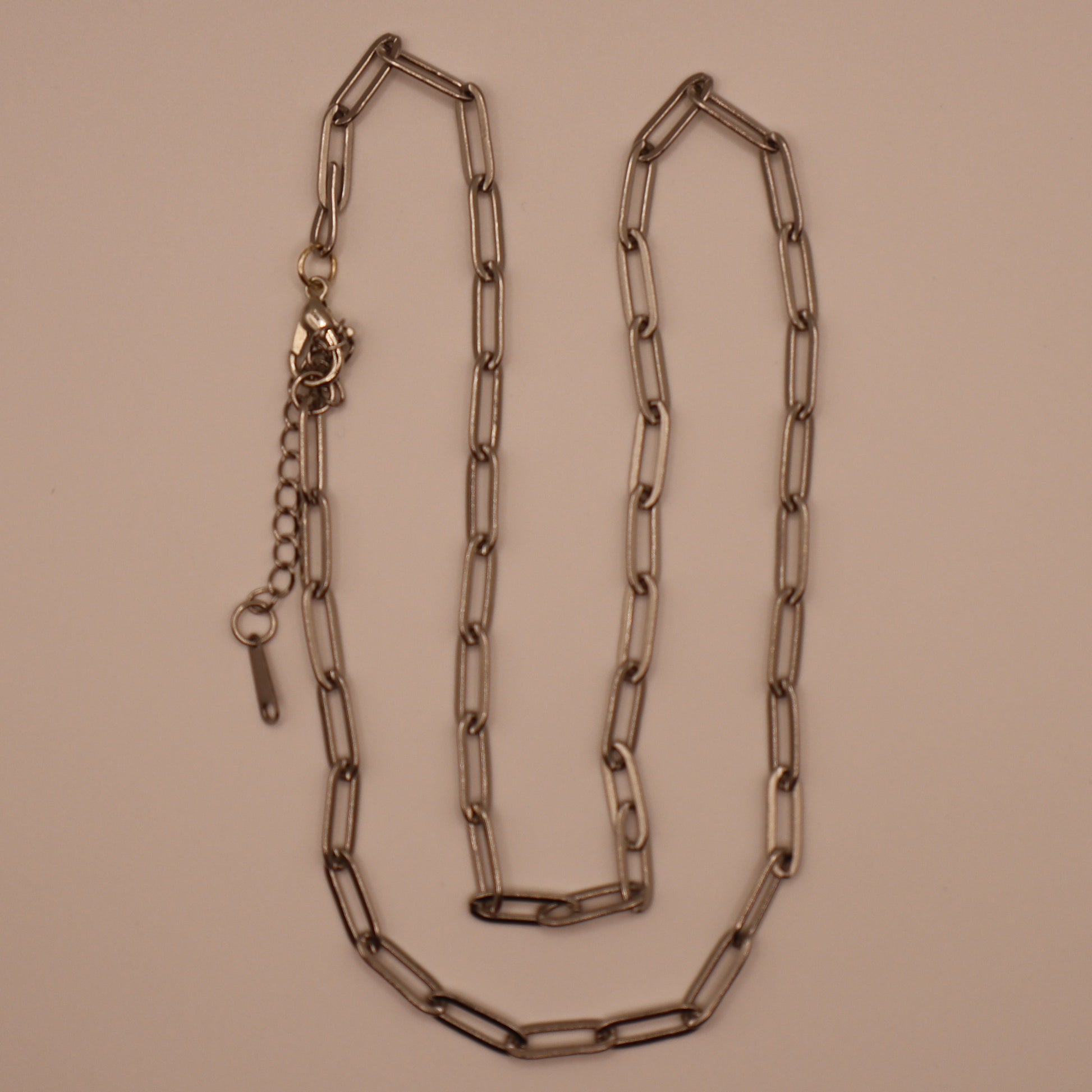 Silver paperclip necklace on a beige background