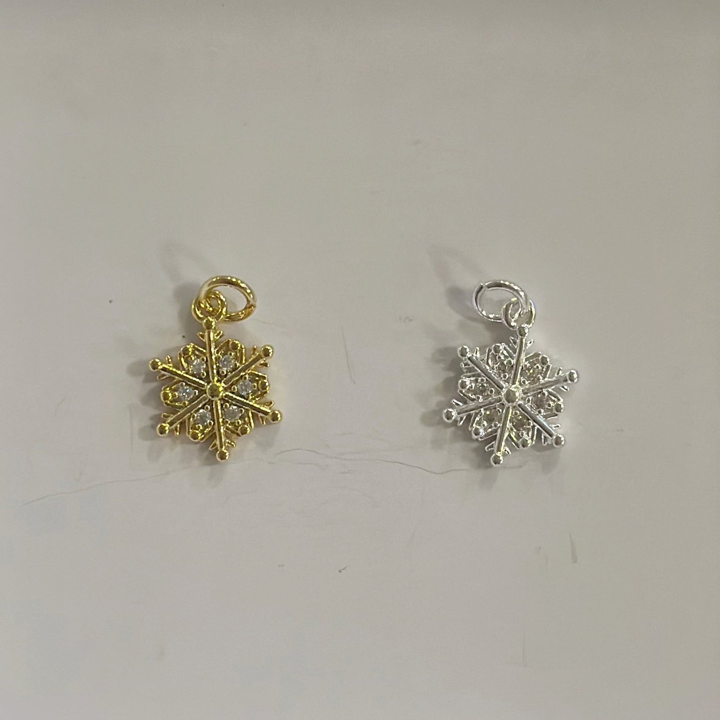 Gold and silver snowflake-shaped charms on a light gray background